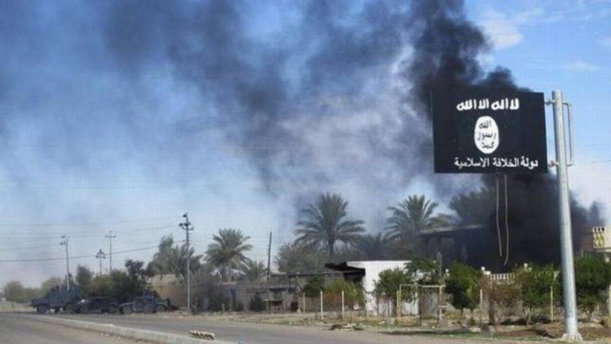 Humo negro tras la bandera de Estado Islámico después de que las fuerzas iraquís y chiís tomasen el control de Saadiya, el 24 de noviembre.-Foto: STRINGER IRAQ / REUTERS