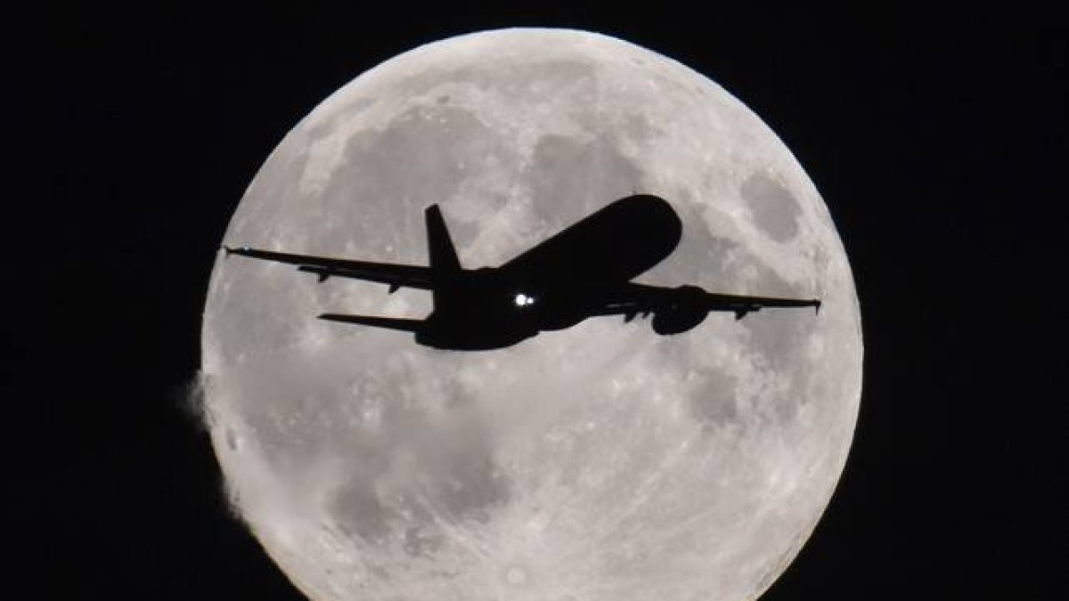Un avión se acerca al aeropuerto de Heathrow (Londres) con la luna llena al fondo.-Foto: REUTERS / TOBY MELVILLE