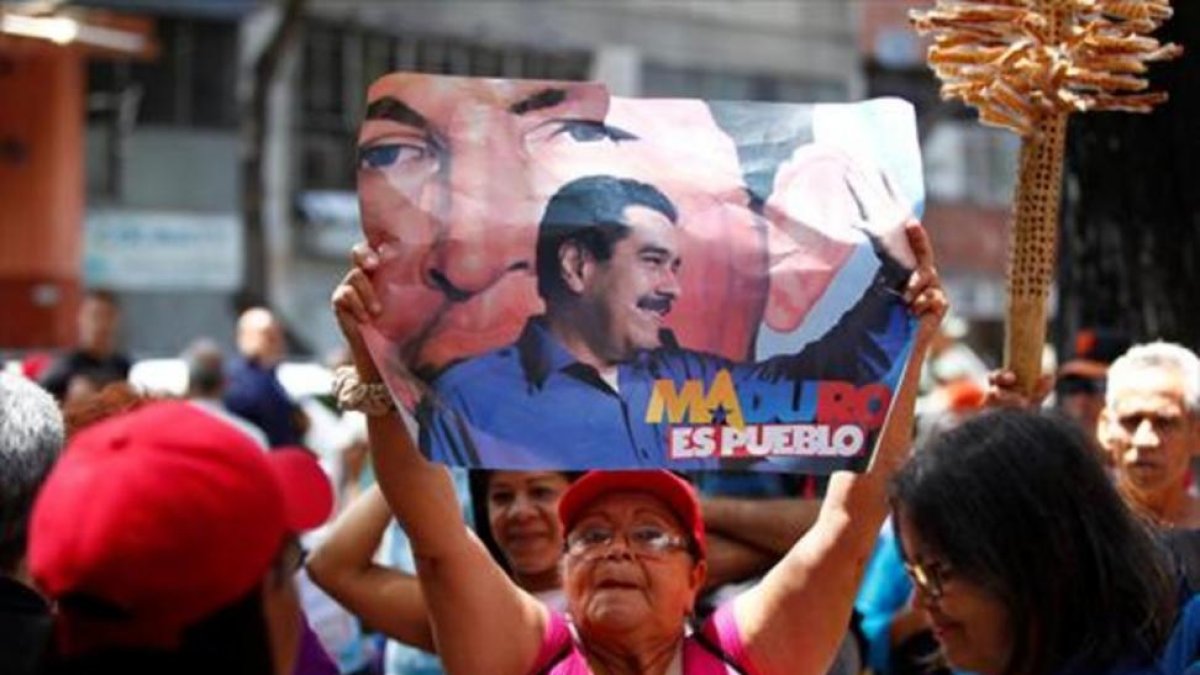 Una mujer, con una pancarta de apoyo a Maduro, el domingo, en Caracas-REUTERS / CHRISTIAN VERÓN
