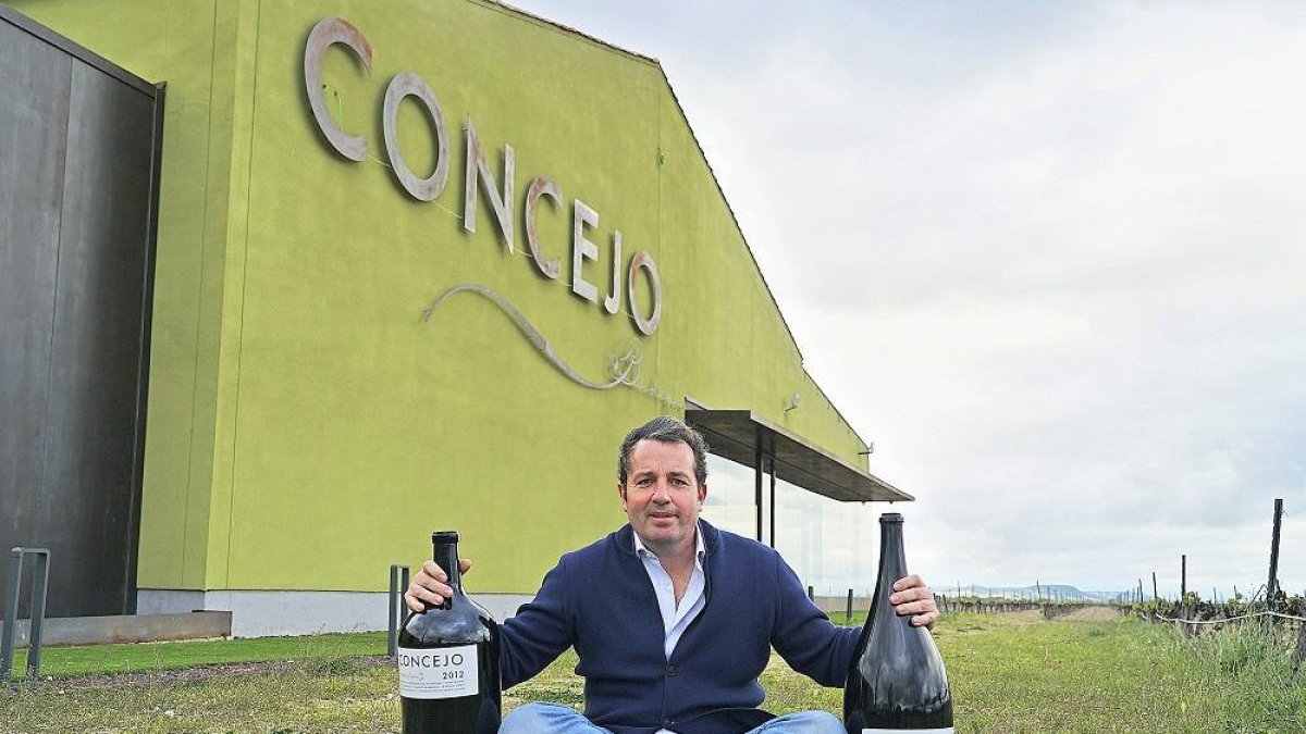 Enrique Concejo posa con dos de sus vinos frente a las instalaciones de su bodega.-