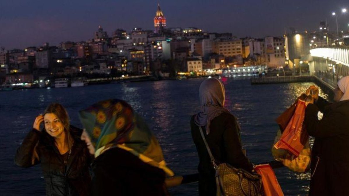 Varias mujeres con pañuelo y sin él fotografían el paisaje de Estambul desde el puente de Galata, el 23 de febrero.-GETTY IMAGES / CHRIS MCGRATH