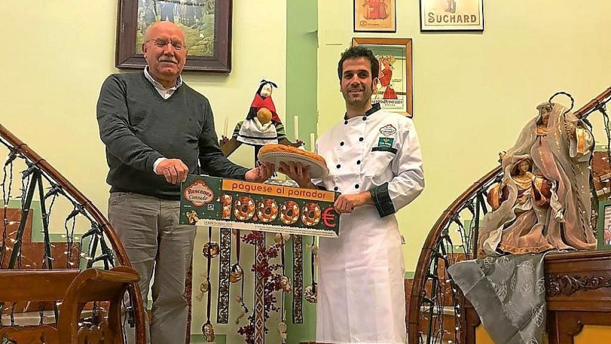 Manuel González y su hijo Sergio González, junto con uno de los roscones y el cheque del premio.-E. M.