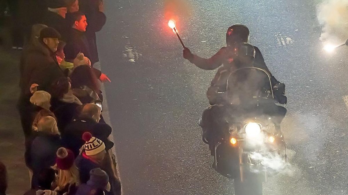 Un motorista y su acompañante emergen entre el humo de la antorcha.-