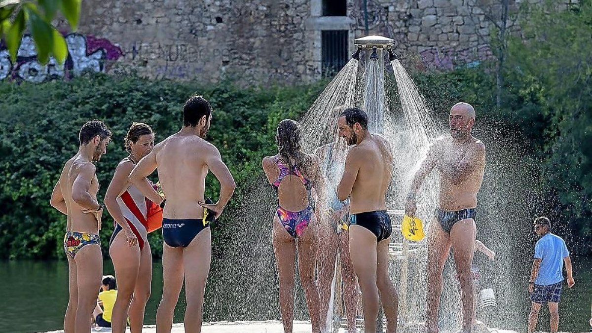 Bañistas en la playa de Las Moreras protegiéndose del calor en la ducha.-PABLO REQUEJO / PHOTOGENIC