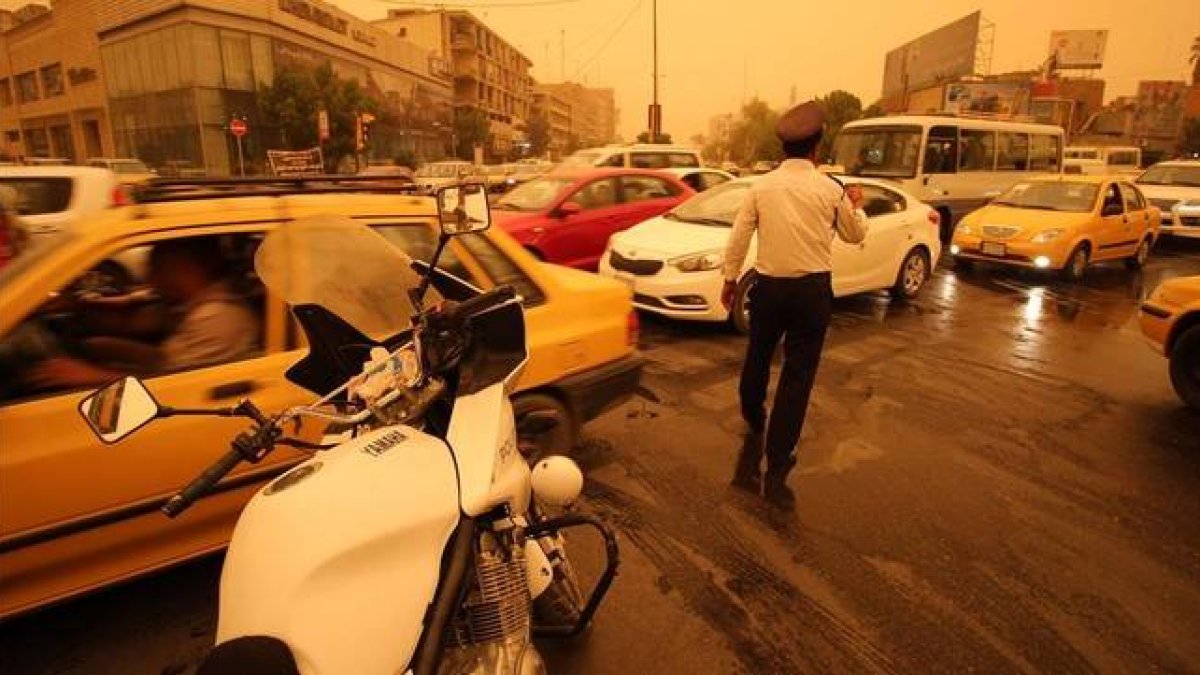 Un policía iraquí organiza el tráfico en Bagdad en medio de una tormenta de arena.-AFP / HAIDAR MOHAMED