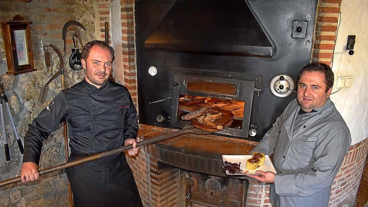 Alfonso y Julio, junto al horno de asar de Los Tarantos y uno de los platos de la bodega-restaurante.-ARGICOMUNICACIÓN