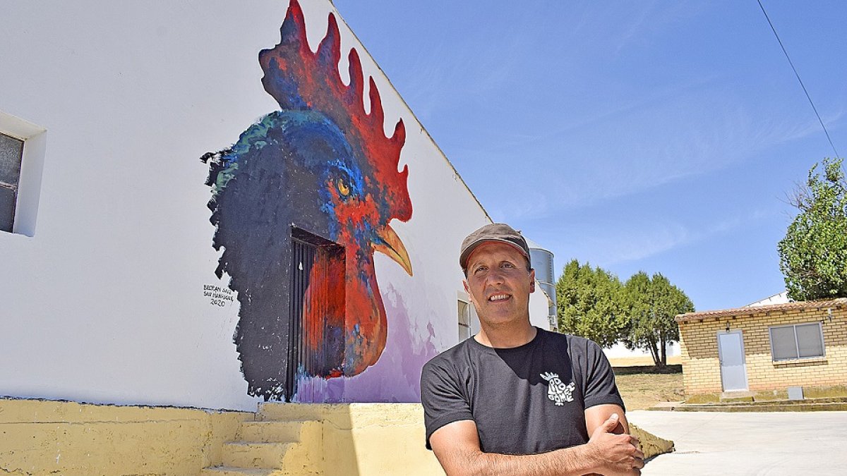 Rodrigo Barriuso, delante de uno de los murales de Villangómez, que es una alegoría a las granjas avícolas de la localidad. / ArgiComunicación