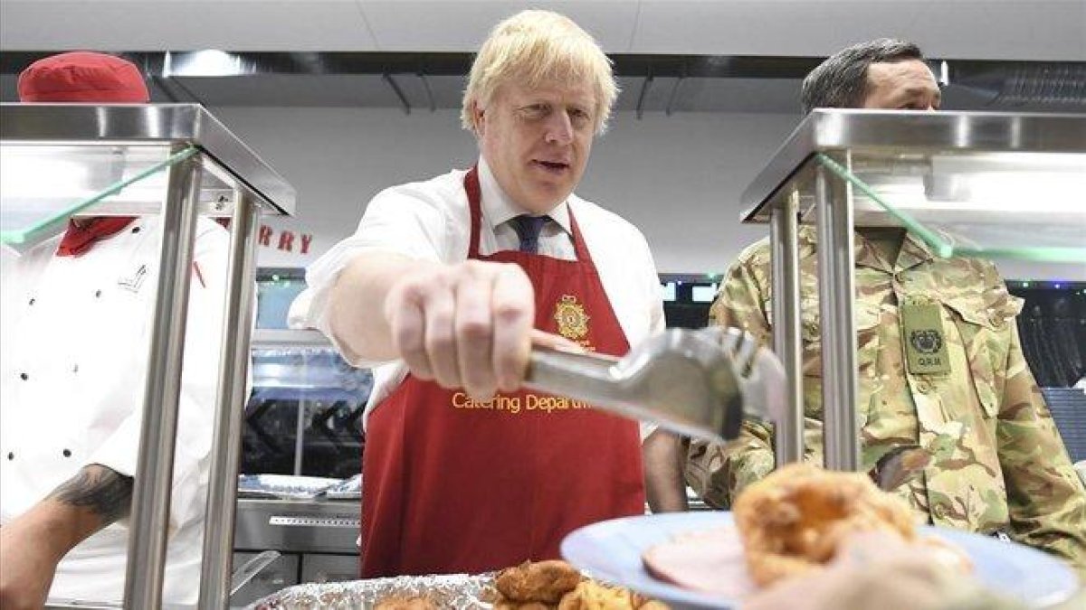 El primer ministro británico, Boris Johnson, sirve el sábado comida de Navidad a las tropas británicas estacionadas en Estonia.-AP / STEFAN ROUSSEAU