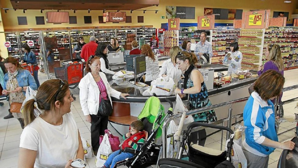 Varias personas realizan sus compras en un supermercado.-J.M. LOSTAU