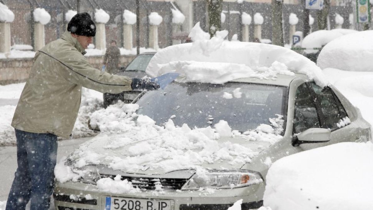 Un hombre retira la nieve de su coche en Burgos.-ICAL