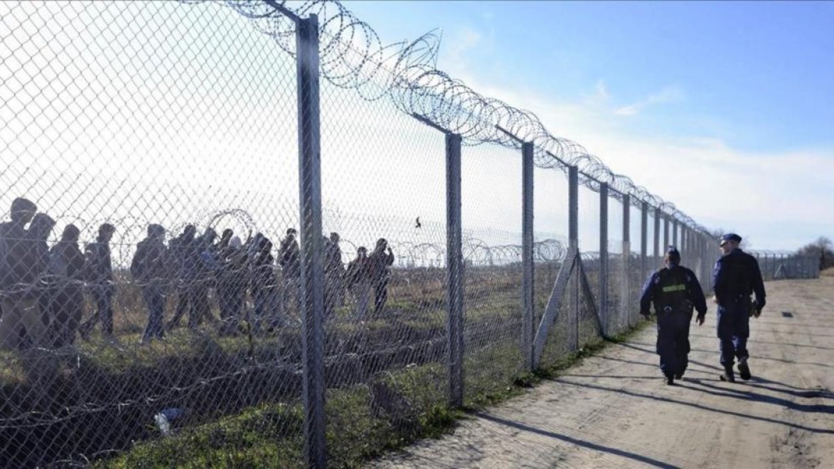 Policías húngaros vigilan a refugiados tras una valla temporal en la frontera con Serbia, cerca de Morahalom, el 22 de febrero del 2016.-ZOLTAN GERGELY KELEMEN