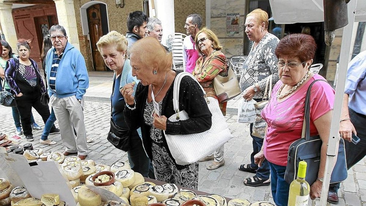 Vecinos y visitantes degustan queso en uno de los expositores del mercado en una anterior edición.-J.M. LOSTAU