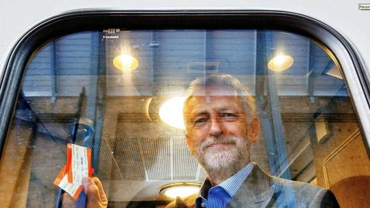 Jeremy Corbyn fotografiado en el interior de un vagón de tren sujetando dos billetes.-REX SHUTTERSTOCK / TOLGA AKMEN