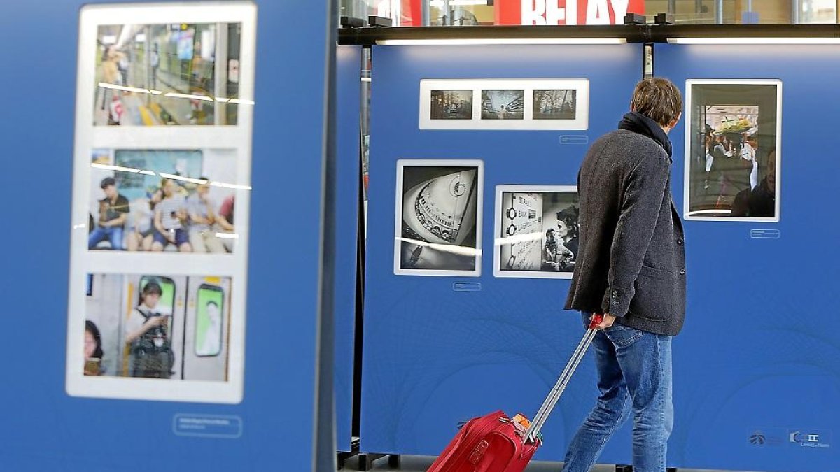 Un viajero contempla una de las fotografías de la exposición en la estación de Campo Grande.-J.M. LOSTAU