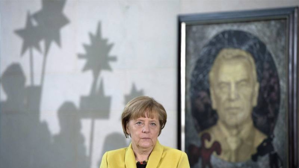 La canciller alemana, Angela Merkel, ante un retrato del excanciller Gerhard Schroeder durante una recepción, hoy, en Berlín.-Foto: EFE