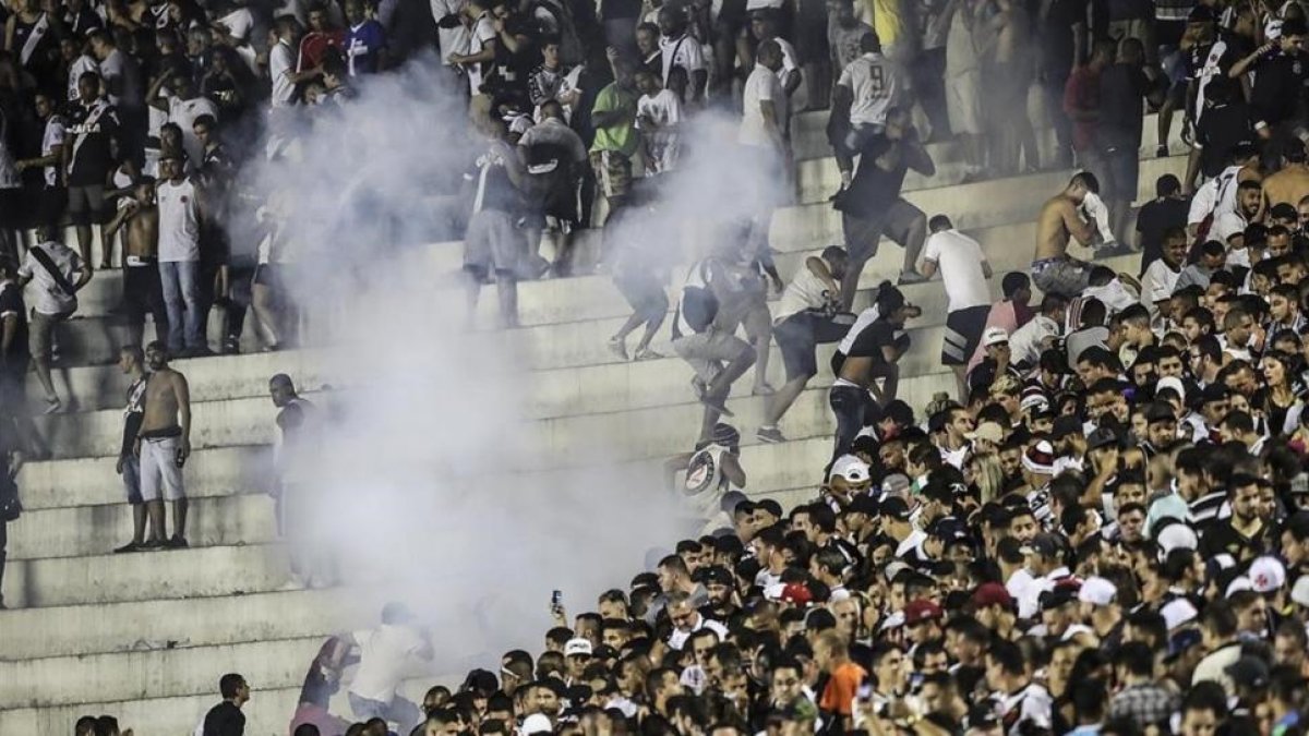 Los aficionados de Vasco da Gama se enfrentan con la policía durante el partido de su equipo contra el Flamengo.-EFE / ANTONIO LACERDA