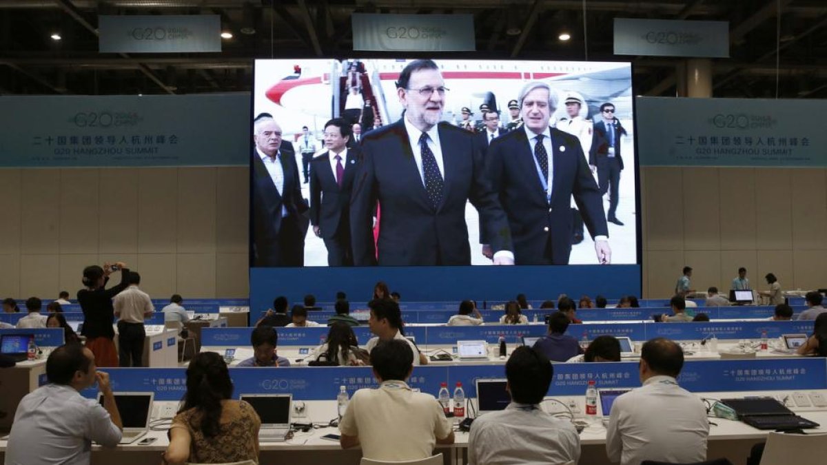 Los periodistas siguen desde la sala de prensa la llegada del presidente del Gobierno español en funciones, Mariano Rajoy (i), al aeropuerto Internacional de Hangzhou Xiaoshan, para participar en la cumbre del G20.-EFE / JUAN CARLOS HIDALGO