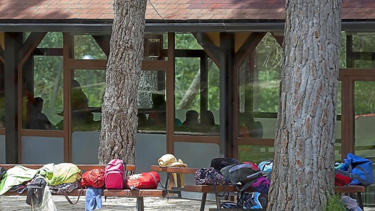 Niños y monitores del campamento en un pabellón, ayer en el área de ocio de Hornillos de Eresma. En el exterior, mochilas y sacos de dormir.-NURIA MONGIL
