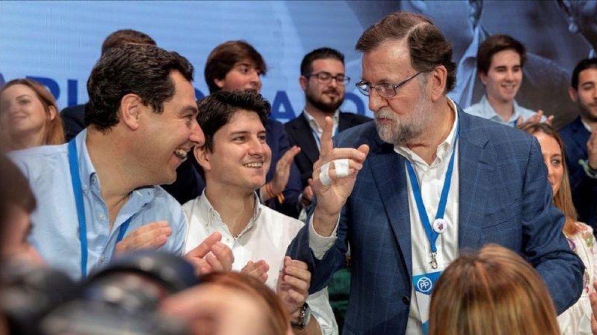 Mariano Rajoy habla con el líder del PP andaluz, Juanma Moreno, y el presidente de Nuevas Generaciones, Diego Gago, en la convención de Sevilla.-EFE / JULIO MUÑOZ