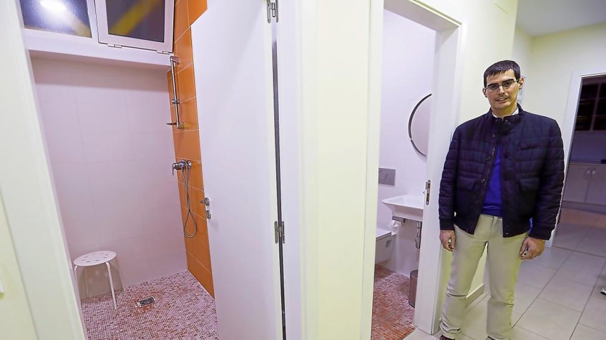 El párroco Luis Miguel Rojo junto con dos de los aseos del centro de higiene de La Milagrosa.-J.M.LOSTAU