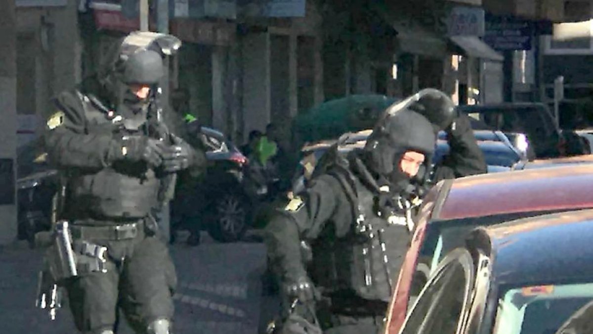 Dos de los agentes, pertrechados con el equipo de las operaciones especiales se dirigen al domicilio.-ECB