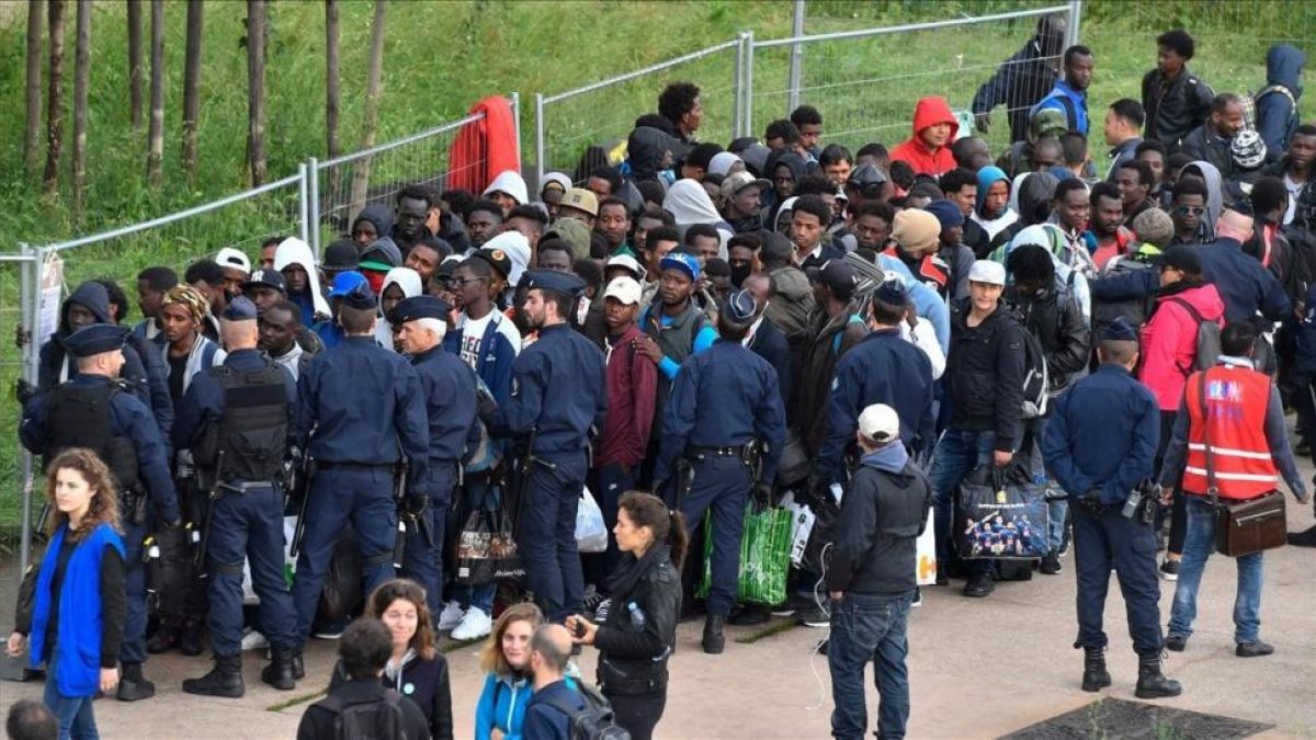 Policías franceses escoltan a los refugiados que han sido desalojados del campamento cercano a París.-/ AFP / GERARD JULIEN
