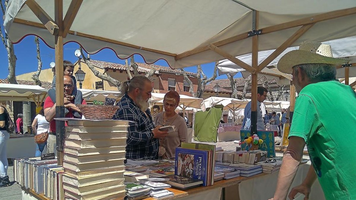 Visitantes ojean un libro en uno de los dieciocho expositores de las librerías locales de Urueña que celebró ayer el X aniversario de la Villa del Libro.-EL MUNDO