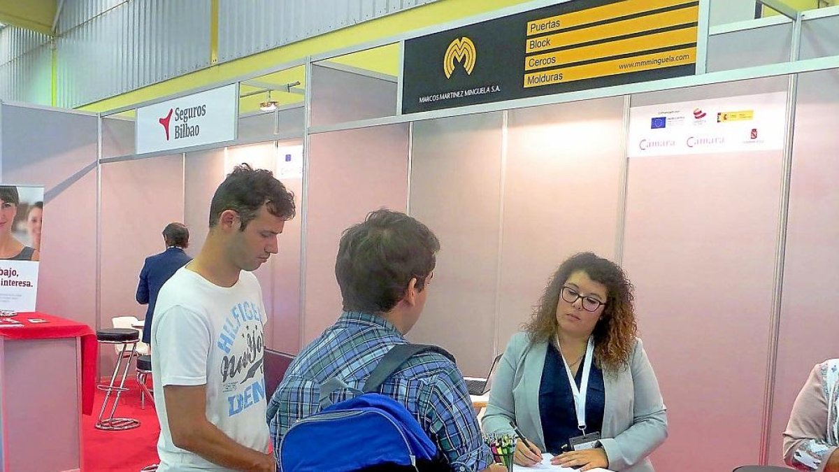 Dos jóvenes presentan su currículum en el expositor de una de las empresas participantes, ayer en Íscar.-EL MUNDO