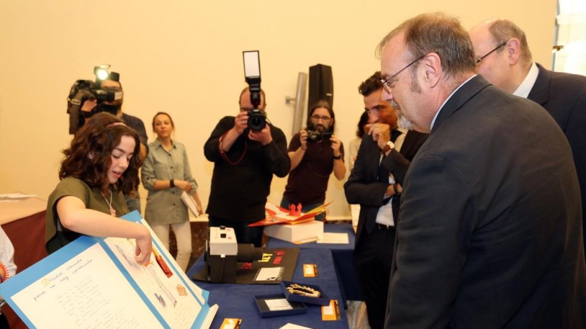 El consejero de Educación, Fernando Rey, escucha los detalles del trabajo galardonado con el premio '¿Qué es un rey para ti?', por parte de su autora, Fátima López-Rubén Cacho / ICAL