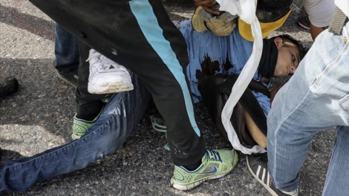 El joven David José Vallenilla es atendido tras recibir el disparo.-MIGUEL GUTIÉRREZ/FEFE