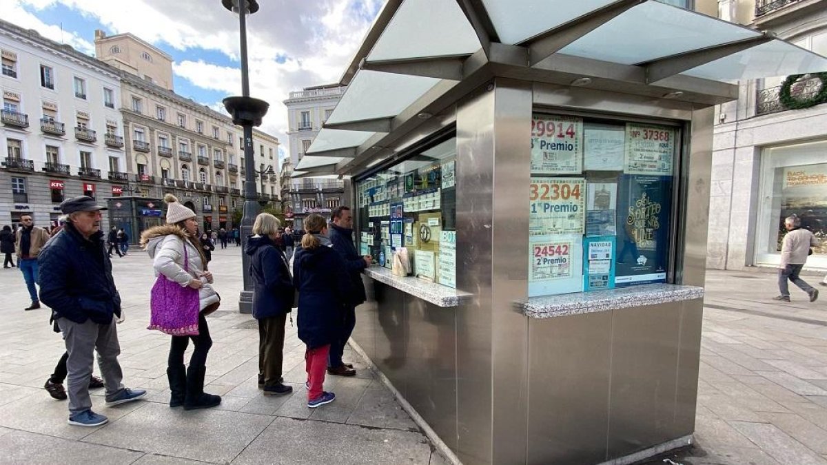 Varias personas hacen cola para comprar un décimo de Lotería de Navidad en una Administración en la plaza de Puerta del Sol, en Madrid (España), a 18 de noviembre de 2019.-EUROPA PRESS