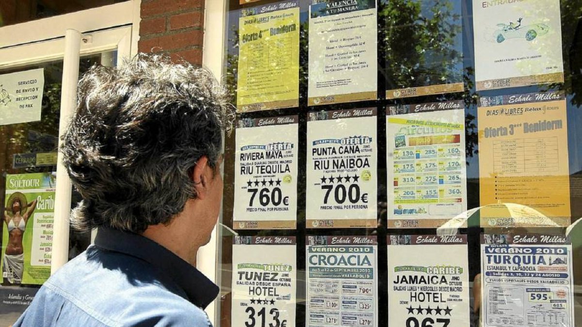 Un señor consulta los carteles de una agencia de viajes