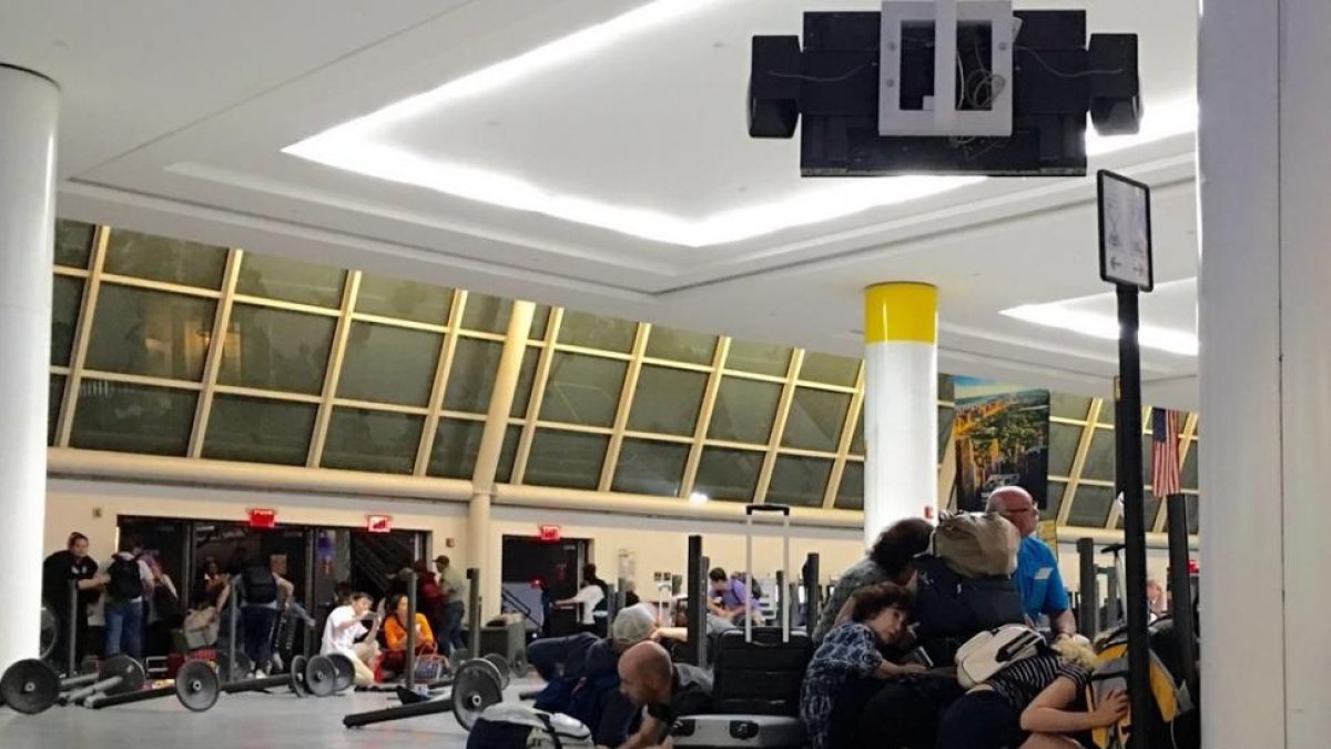 Pasajeros del aeropuerto JFK de Nueva York se protegen mientras la policía busca a un presunto tirador, la pasada madrugada.-AFP