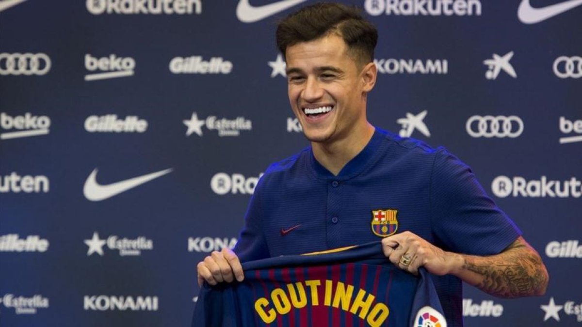 Philippe Coutinho sostiene la camiseta con su nombre durante el acto de presentación.-JORDI COTRINA
