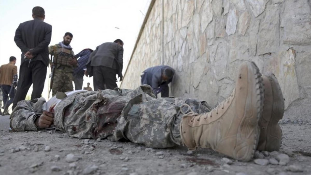 Militares inspeccionan el cadáver de un miliciano en la sede del Ministerio del Interior afgano, en Kabul.-/ RAHMAT GUL