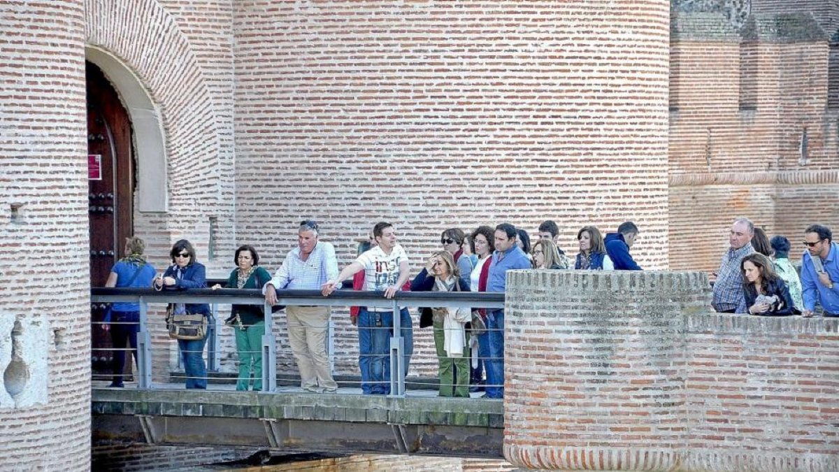 Un grupo de turistas, acompañados por un guía, se asoma a la pasarela del Castillo de La Mota, para observar el foso-SANTIAGO G. DEL CAMPO