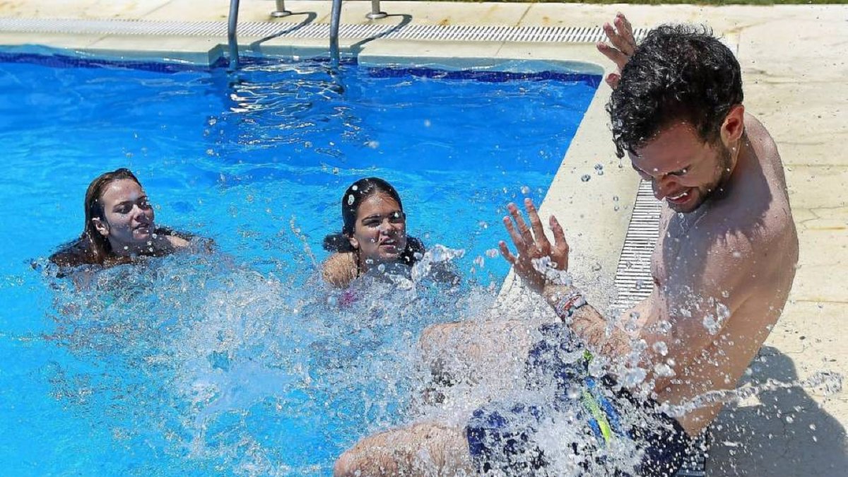 Tres jóvenes se divierten y se refrescan en una piscina privada para hacer frente al calor en Valladolid.-J. M. Lostau