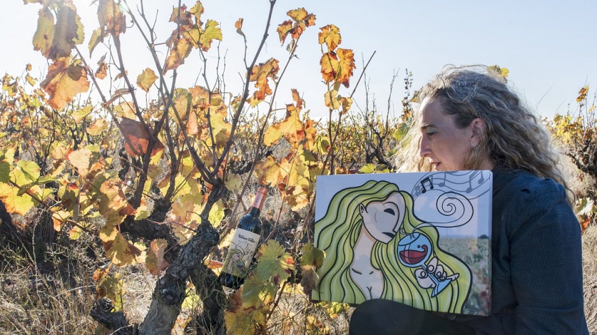Ana Casis, en su viña, con el cuadro que se representa en la etiqueta de su nuevo vino, Los Turuntales Autor, elaborado con uva negro saurí. / ÁNGEL MORENO.