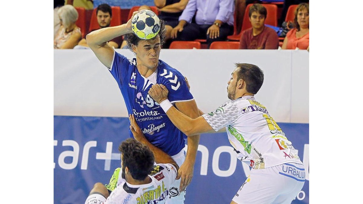 Dos jugadores del Puente Genil intentan frenar el ataque del lateral Víctor Rodríguez.-J. M. LOSTAU