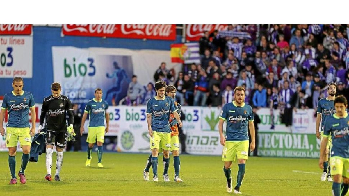 Los jugadores del Real Valladolid abandonan cabizbajos el estadio El Toralín tras la derrota con los aficionados vallisoletanos al fondo-Luis de la Mata