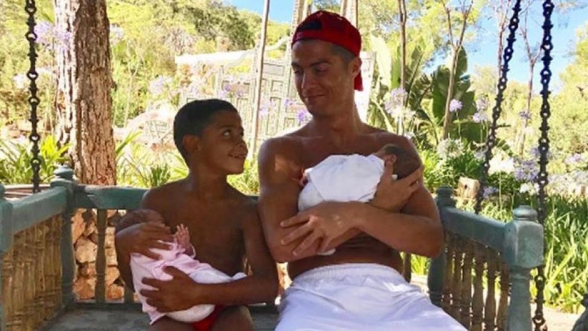 Cristiano Ronaldo sostiene en los brazos al mellizo Mateo mientras sonríe al primogénito, abrazado a Eva.-