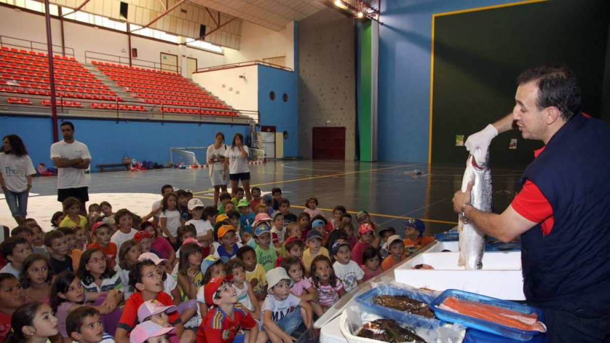 Un pescadero explica a los niños las difentes partes de un pez dentro del Programa Thao contra la obesidad infantil-Ical