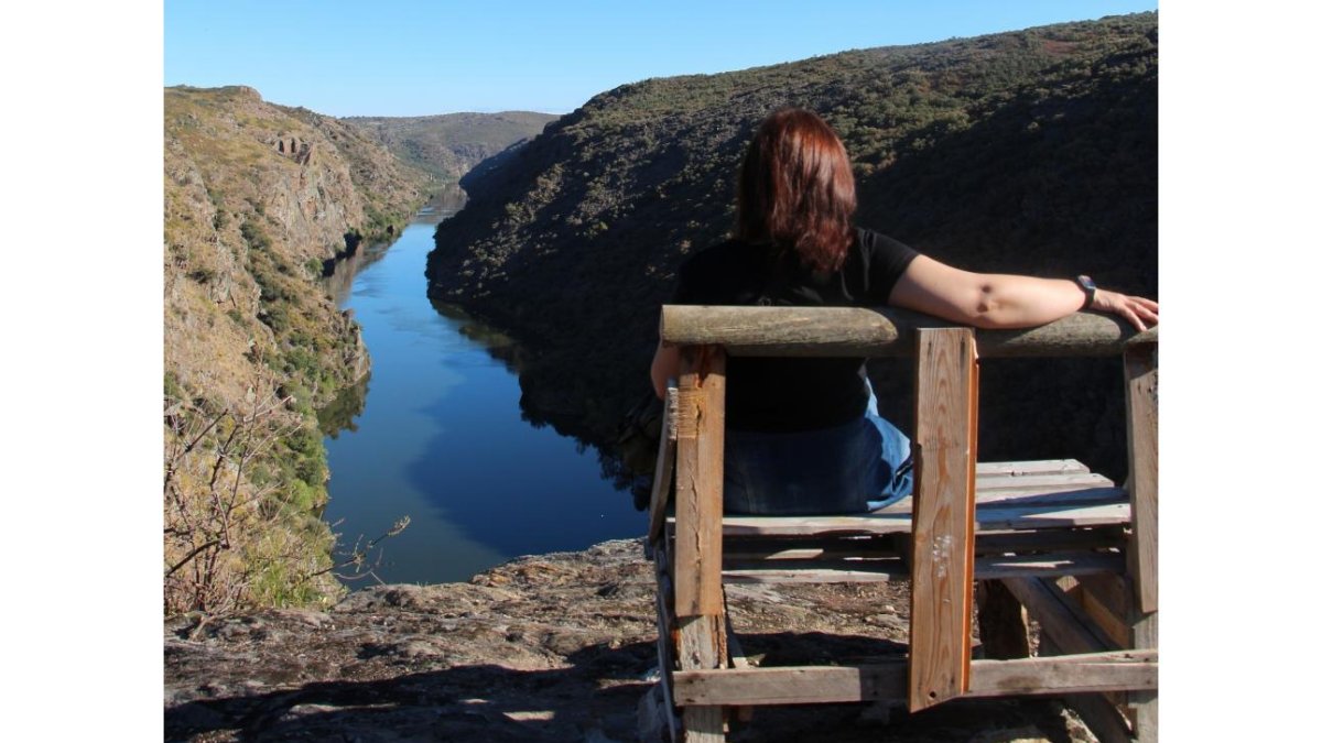Una mujer disfruta del paisaje del Arribe del Duero sentada en el banco El Hullón. A la d. indicador colocado en el camino.-J.L.C.