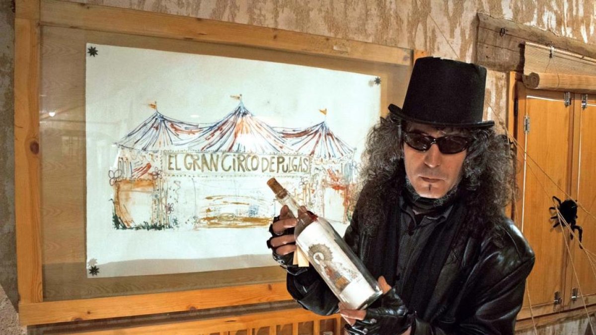 El polifacético artista Miguel Ángel Maroto, con uno de sus célebres grabados embotellados, y junto al circo de pulgas de su Taller-Galería Numen de Cabañas de Polendos (Segovia).-ARGICOMUNICACIÓN