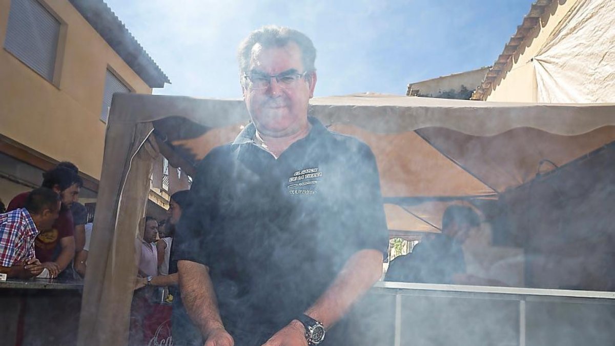Un hombre cocina en las brasas pincho de lechazo.-MIGUEL ÁNGEL SANTOS