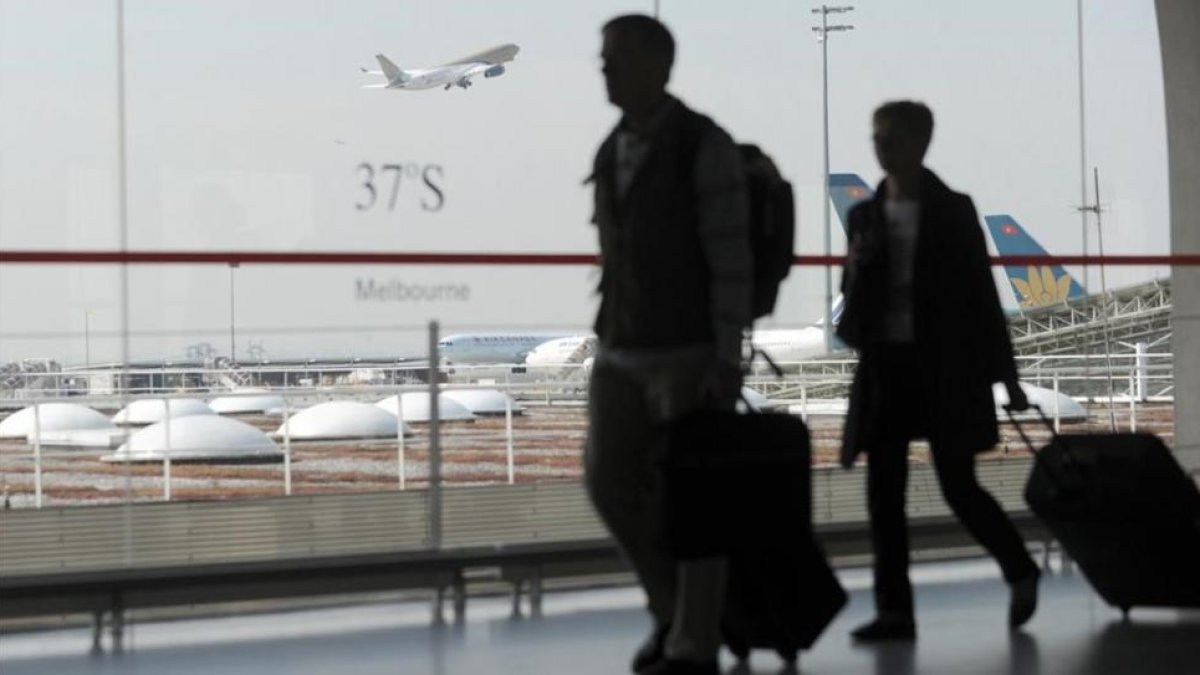 Unos pasajeros caminan con su equipaje en el aeropuerto de Roissy-Charles de Gaulle, en París (Francia).-FRED DUFOUR