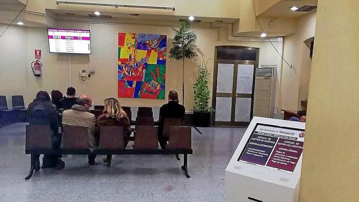 Varias personas esperan en las oficinas de la plaza de Santa Ana tras instalarse el nuevo sistema de espera.-E.M.