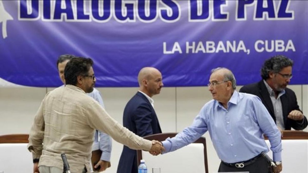 El comandante de las FARC y líder del equipo negociador de paz Luciano Marin 'Ivan Marquez' estrecha la mano del jefe negociador del Gobierno colombiano  Humberto de la Calle, el viernes.-ERNESTO MASTRASCUSA