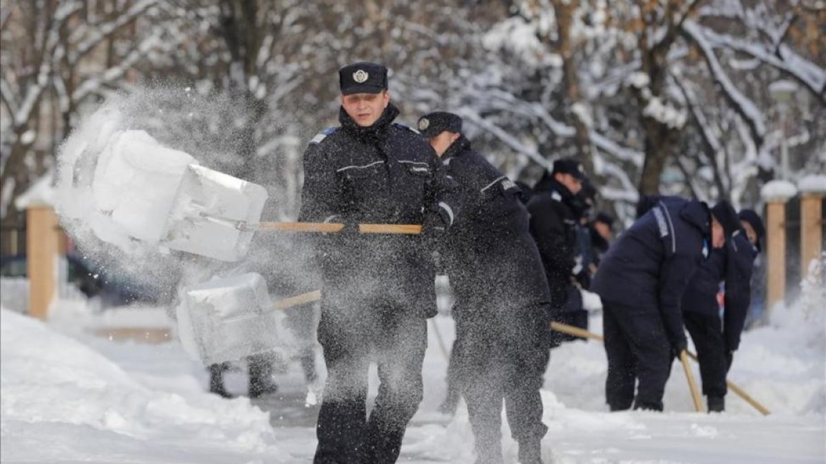 Gendarmes rumanos limpian la nieve en los accesos a una escuela en Bucarest.-AP / VADIM GHIRDA