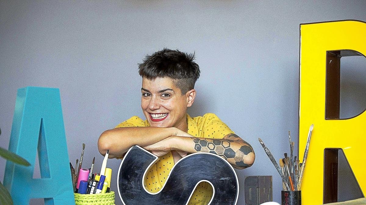 La diseñadora gráfica vallisoletana Laura Asensio posa rodeada de letras, tema central de la exposición de la que es comisaria.-ICAL